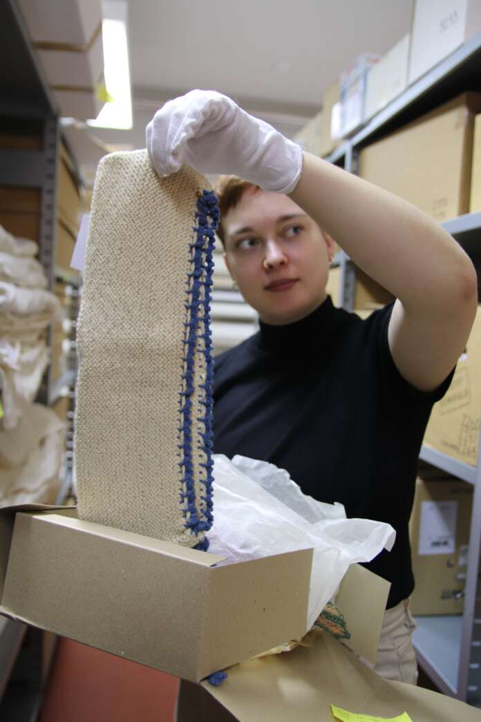 Museoesineitä kosketaan hansikkain ja ne säilötään silkkipaperiin. Museoharjoittelija Viivi Kainulainen pohtii, mikä kyseinen käsityö mahtaa olla.